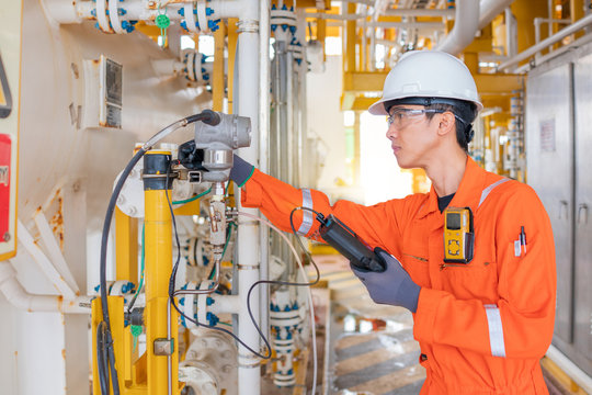 Instrument technician operator calibrate pressure transmitter with hand held calibrator on offshore oil and gas central processing platform.
