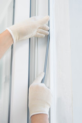 a gloved craftsman lays a rubber seal when installing a new plastic window, close-up