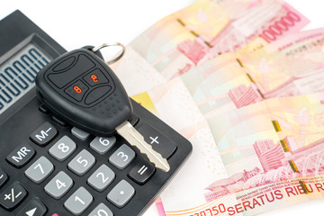 Pile of money beneath a calculator and a car key