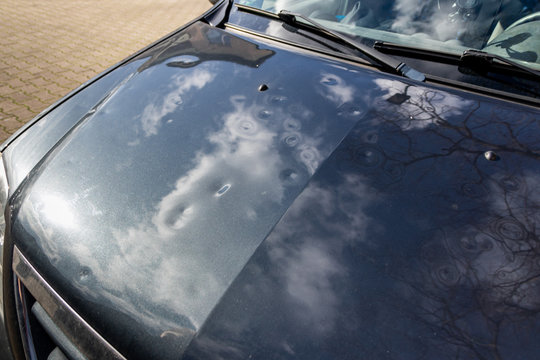 Motorhaube eines grauen PKW mit Hagelschaden zeigt nach einem Hagelschauer viele Dellen und Beulen in der Motorhaube vom Hagel, Eisregen und extremes Wetter mit Sturmschaden f&uuml;r die Versicherung