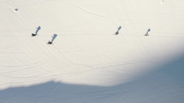 AERIAL: Birds eye view down on people splitboarding through a snowy landscape. Sunny day. Zillertal, Austria