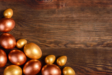 Easter eggs gold and bronze and Easter cake on a dark background