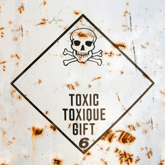 danger sign with a skull on rusted painted surface, inside the rhombus shape frame