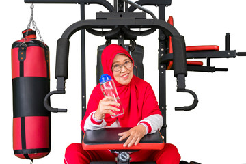 Obraz premium Senior muslim woman sitting on gym machine