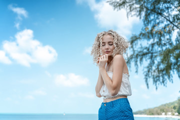 Beautiful young slim curly girl woman blonde enjoys nature on the seashore, romantic portrait