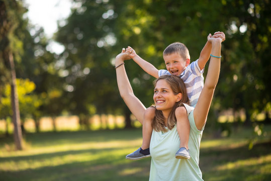 Mother Carrying Cheerful Son On Her Shoulders