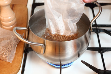 Adding plastic sachets into boiling water. Cooking buckwheat groats on gas stove.