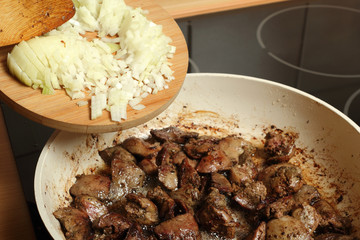 Cooking Chicken Liver. Adding diced onion into fried liver.