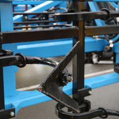 Black metal plow cultivator on a blue harrow.