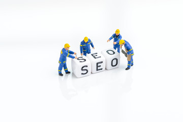 SEO, Search Engine Optimization, building the website with keywords concept, miniature people technology staffs building cube small block the word SEO on copy space white background
