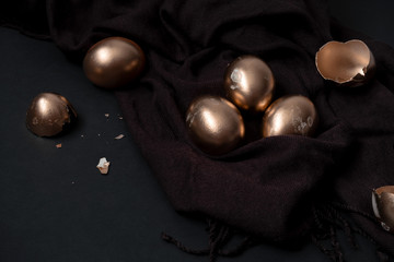 top view golden easter eggs and egg shells on a black background