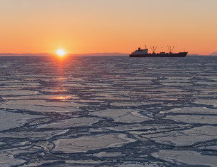 Dawn in the Sea of Okhotsk, ship on the horizon, in the sea ice