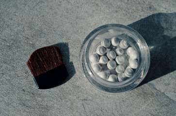White pearl ball face powder for highlighting on a gray background, top view, close up
