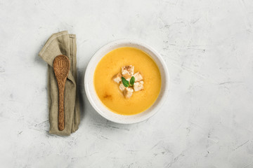 Pumpkin and carrot soup with cream and spinach with crackers on a white background.