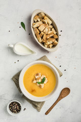 Pumpkin and carrot soup with cream and spinach with crackers on a white background.