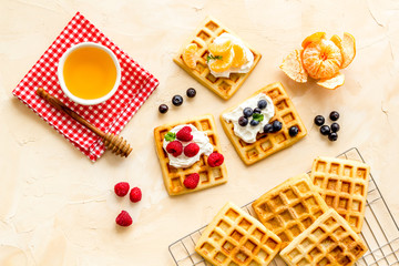 Belgian waffles with creamy cheese and berries on beige background top-down