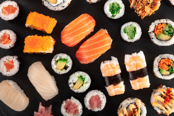 Large sushi set, shot from the top on a black background. A flat lay of various maki, nigiri and rolls
