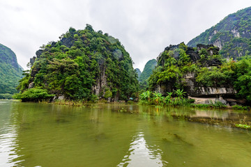 Tam Coc National Park - Tourists traveling in boats along the Ngo Dong River at Ninh Binh Province, Trang An landscape complex, Vietnam - Landscape formed by karst towers and rice fields