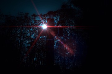 Cross in a cemetery with a rising sun scene