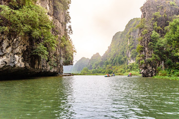 Fototapeta na wymiar Tam Coc National Park - Tourists traveling in boats along the Ngo Dong River at Ninh Binh Province, Trang An landscape complex, Vietnam - Landscape formed by karst towers and rice fields