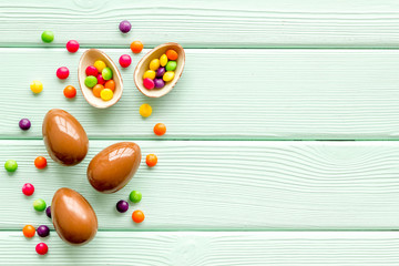 Fototapeta na wymiar Chocolate eggs - Easter symbol - frame on green wooden background top-down copy space