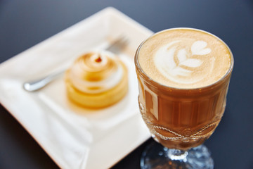a glass of coffee with foam with a pattern on a gray background with a framed 