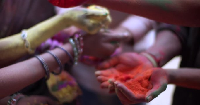 Extreme closeup handheld CU, hands of Indian people, men and women, holding multi colored powder or gulal in plams of their hands in a circle for celebrating Holi, traditional Indian festival of color