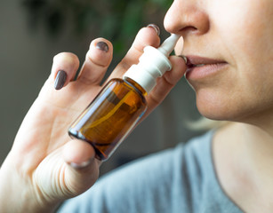 Woman using nasal spray close up. Health care concept.