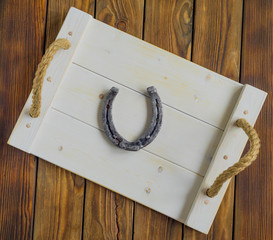 Horseshoe on a white tray on an old wood table. Symbol of luck.