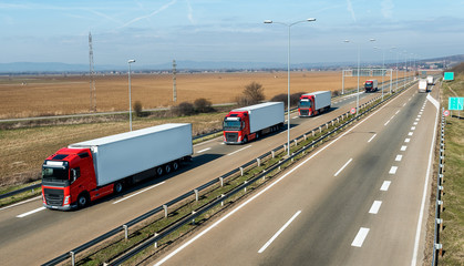 Convoy of transportation trucks passing on a highway on a bright blue day. Highway transportation...