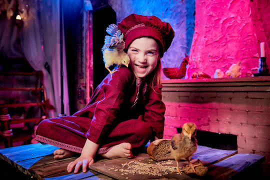 Small girl with little chicken in village interior in the room with wooden table. Easter, holiday and child concept