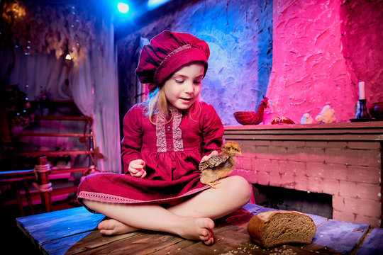 Small girl with little chicken in village interior in the room with wooden table. Easter, holiday and child concept