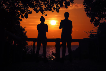 Plakat Silhouette of two women standing watching the sunset on the viewpoint