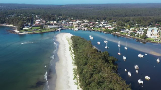 Aerial drone pullback reveal shot of Huskisson on the New South Wales South Coast, Australia, showing Currambene Creek and Jervis Bay on a bright sunny day   
