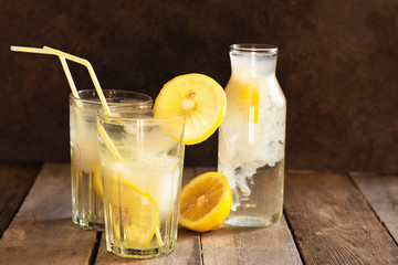 Preparation of the lemonade drink. Lemonade in the jug and lemons with mint on the table outdoor