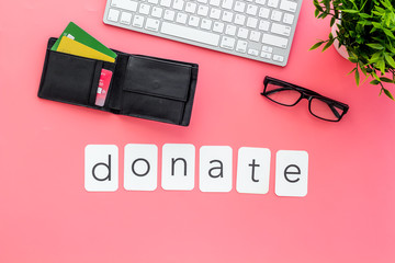 Donate text. Donation online concept with bank card and keyboard on pink background top-down