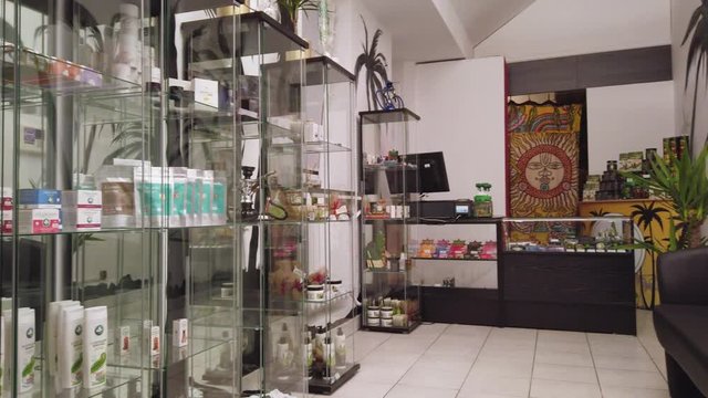 Variety of cannabis products displayed on glass shelves in CBD shop - wide shot