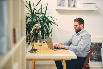 Young male architect sitting at his desk and typing.	