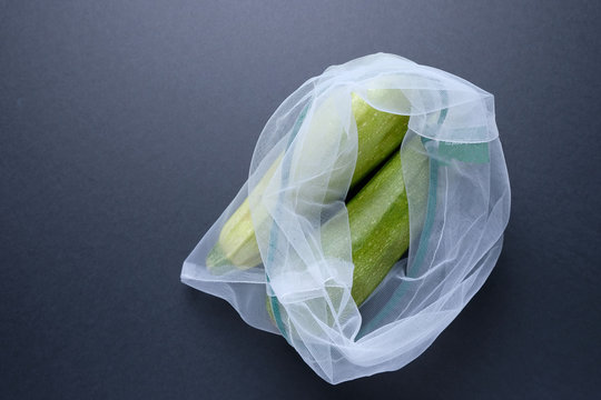 Composition with zucchini in a string bag on a black background. Zero waste.