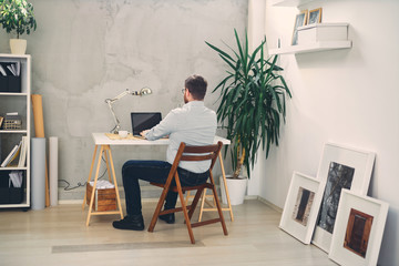 Young male architect sitting at his desk and typing.	