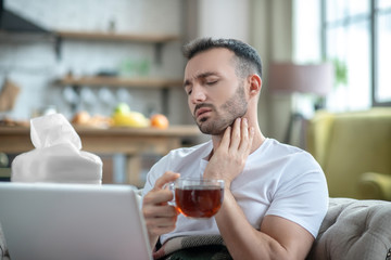 Dark-haired young man having a sore throat