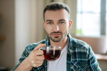 Young man in a checkered shirt having tea