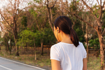 Woman exercise walking in the park listening to music with earphone.