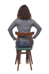 rear view of a woman sitting on chair on white background, hands on hip