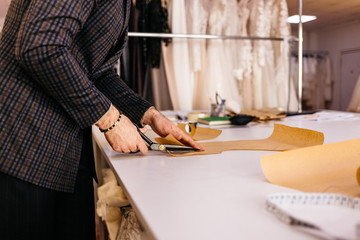 Tailor working at studio cutting fabric, detail of hand with scissors