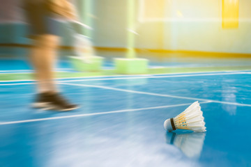 Shuttle cock badminton in the blue court with playing badminton, Image is blurry.