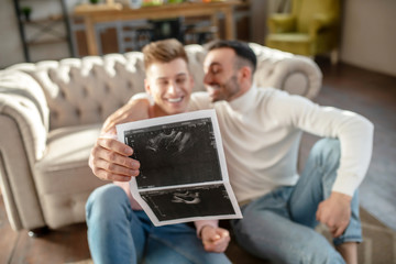Fototapeta premium Ultrasound result in the hand of a young happy man.