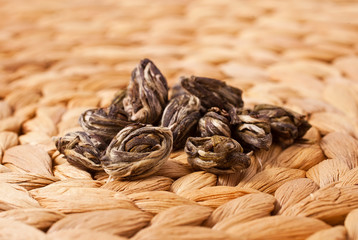 Chinese jasmine tea Mo Li Long Zhu (Jasmine Pearls) on a wicker background.
