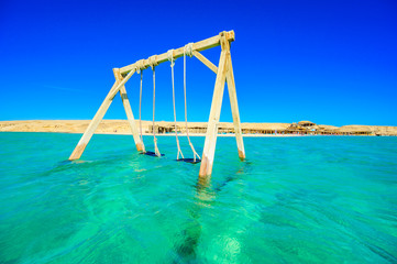 Swing in crystal clear azure water - Orange Bay Beach with white beach - paradise coastline of...