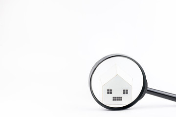 Magnifier glass in front of the model house isolated on white background.Real estate concept. Search and sale of housing. Rent a house and apartment. Sale of property.